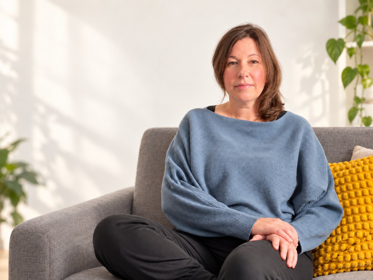 Claudia Widlhofer sitzt lächelnd auf dem Sofa in ihrer Praxis in Wien