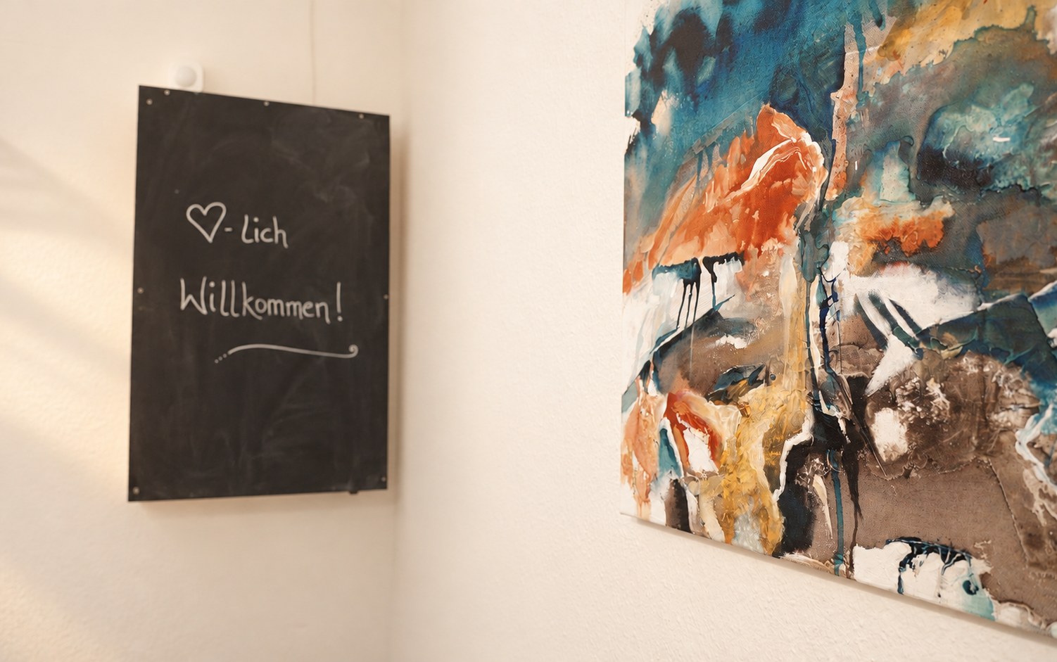 Eingangsbereich der Praxis mit Tafel „Herzlich willkommen“ und einem Gemälde ihres Vaters